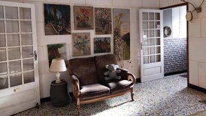 Una habitación con un sofá marrón, una lámpara y arte en la pared.