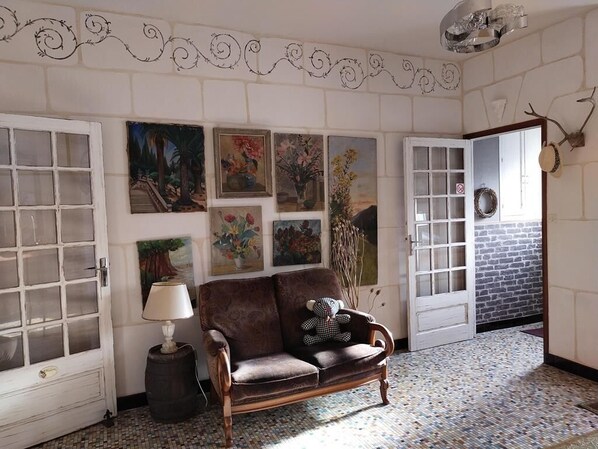 Une pièce avec un canapé marron, une lampe et des œuvres d’art murales.