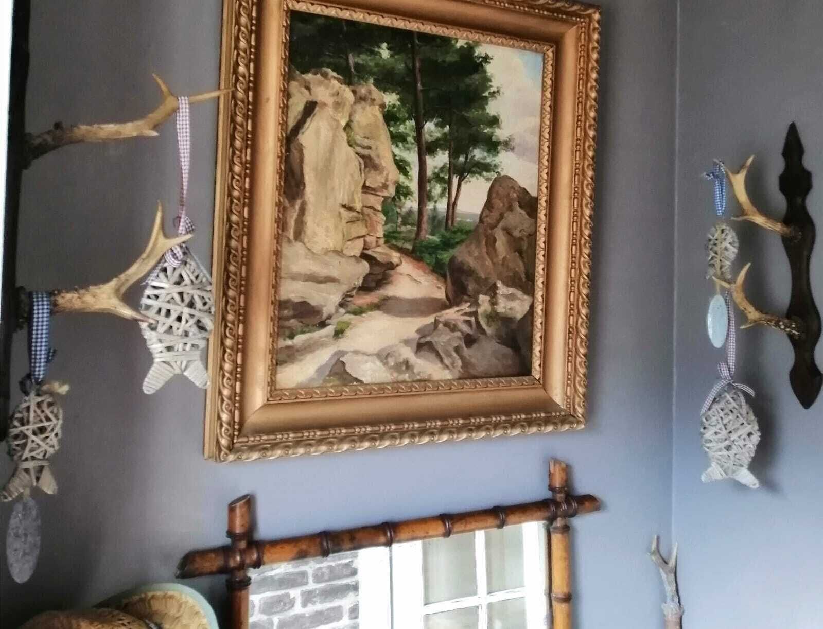 Une pièce décorée d’un tableau encadré représentant un paysage rocheux, de panneaux muraux en bois et d’un banc en bois rustique.