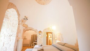 Ein Schlafzimmer mit Steinsturz, einem Bett mit Handtüchern, einem Heizkörper und einer Lampe.