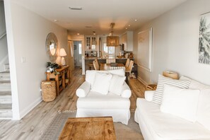 Ein geräumiges Wohnzimmer mit einem weißen Sofa, einem Holztisch und einem Essbereich mit Tisch und Stühlen.
