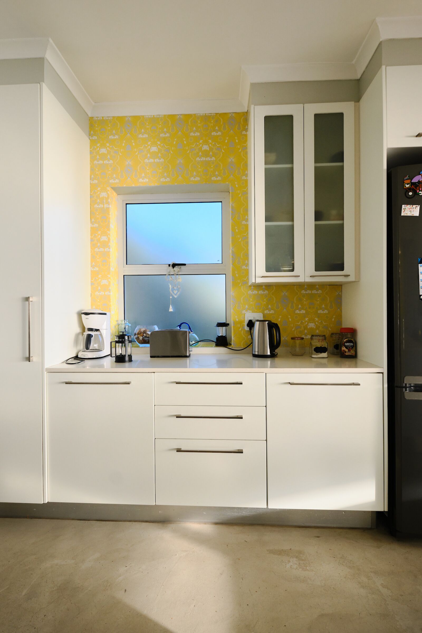 A kitchen with white cabinets, a yellow backsplash, and a window above the sink.
