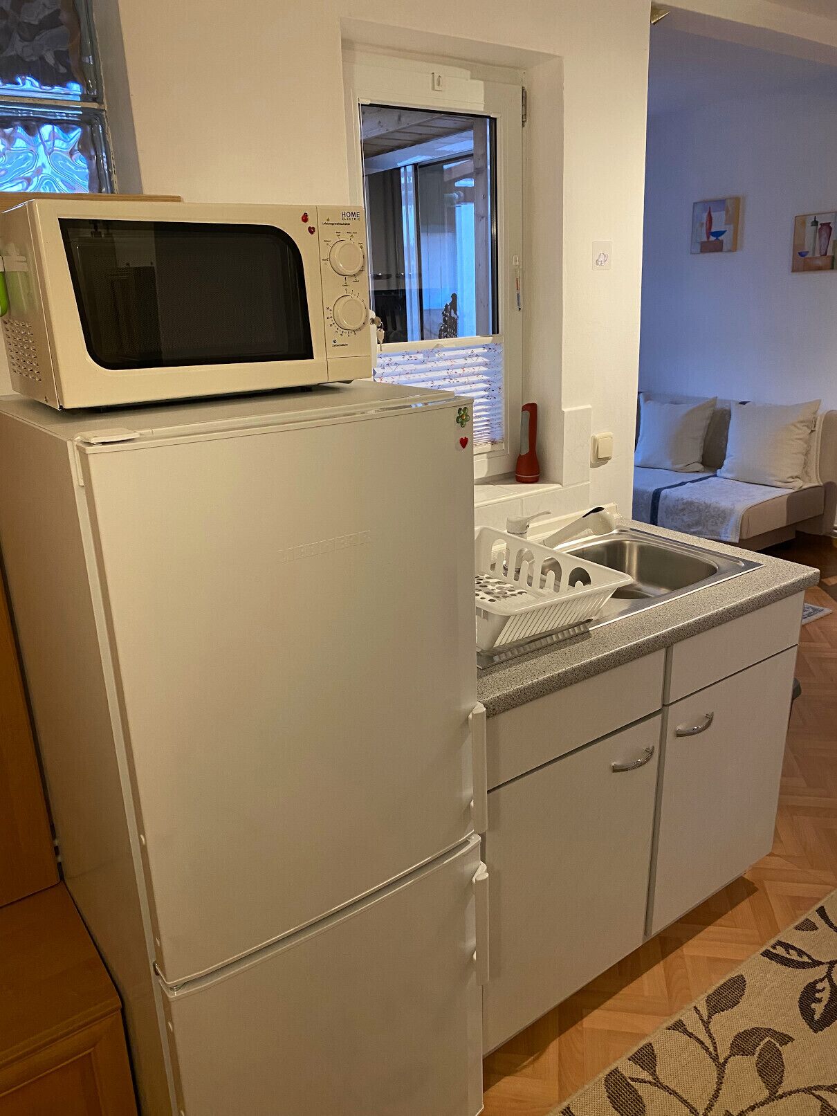 A compact kitchen with a white refrigerator, a microwave, and a sink.