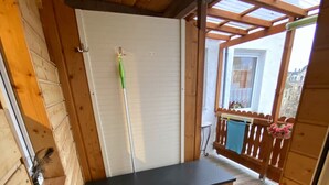 A wooden deck with a bench, a door, and a small table with flowers. - Ferienwohnung Greiz W2 (Greiz)