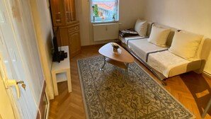 A cozy living room with a sofa, a small table, and a patterned rug. - Ferienwohnung Greiz W2 (Greiz)