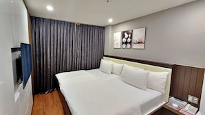 A hotel room with a large bed, a bedside table with a phone and a lamp, and a wall-mounted TV. - HANZ The Moon Hotel 2 (Ho Chi Minh City)