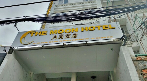 The exterior of The Moon Hotel with its name and contact information.