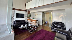 A hotel lobby with a reception desk, black leather sofas, a glass coffee table, and a purple rug. - HANZ The Moon Hotel 2 (Ho Chi Minh City)