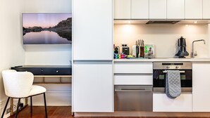 Et moderne køkken med hvide skabe, indbygget ovn og en hængende grydeholder.