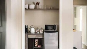 Uma cozinha compacta com micro-ondas, chaleira e prateleiras para guardar utensílios.