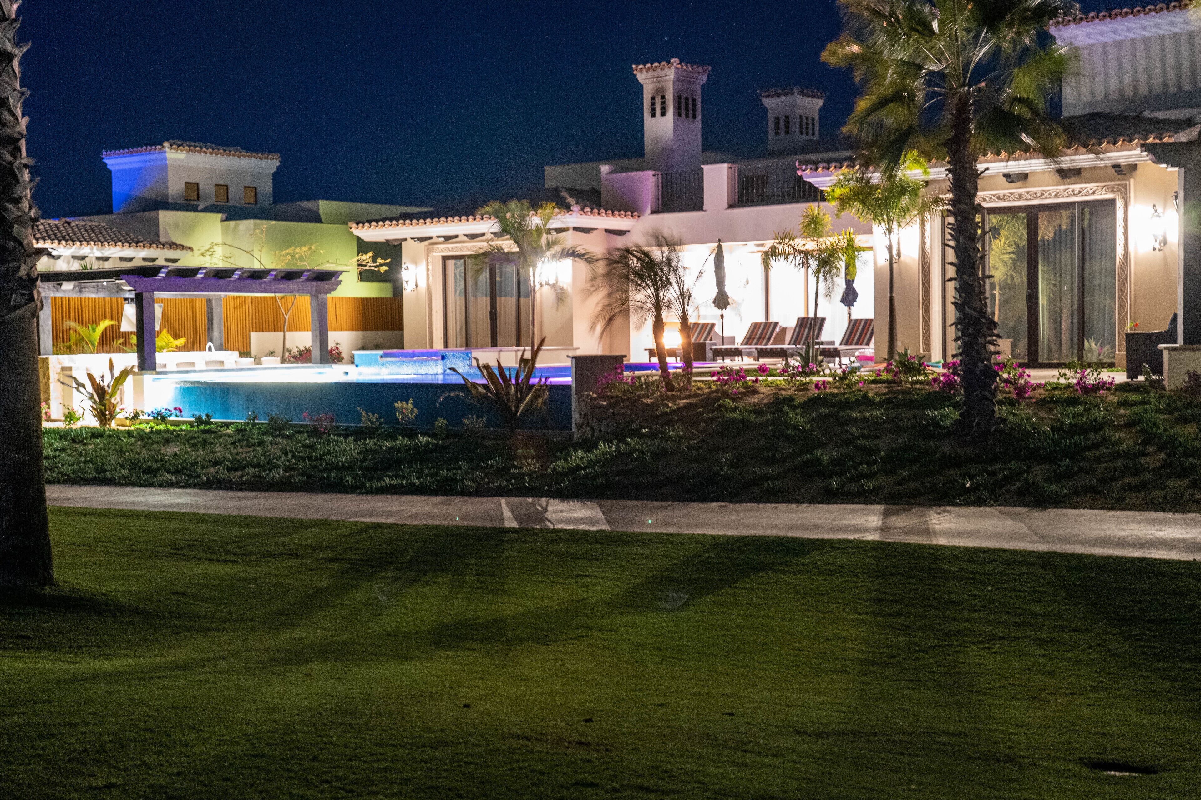 Et veloplyst resort med swimmingpool, palmer og en anlagt have.