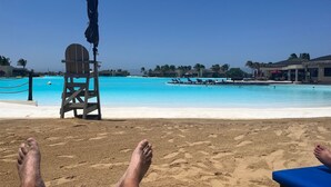 Una playa con una torre de salvavidas, una piscina y sillas de descanso.