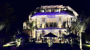 A multi-story building with a pool area, outdoor seating, and a well-lit balcony.