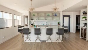 Una cucina moderna con isola centrale, sgabelli da bar e illuminazione a sospensione.