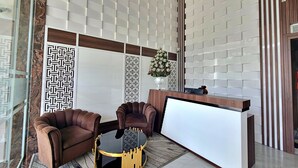 Una zona d'entrada moderna amb taulell de recepció, dues butaques de cuir i una taula rodona.