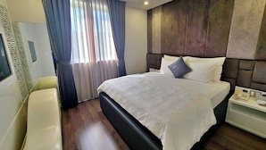 Una habitació d'hotel amb un llit gran, una taula de nit amb un telèfon i una finestra amb cortines.