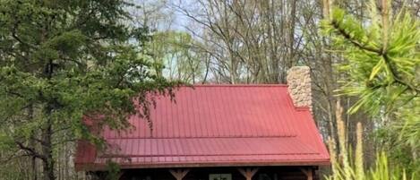 Une cabane rustique avec un toit rouge, un revêtement extérieur en bois et une véranda.