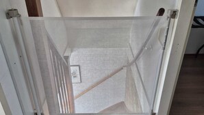 A room with a wooden floor, a white door, and a metal mesh screen.