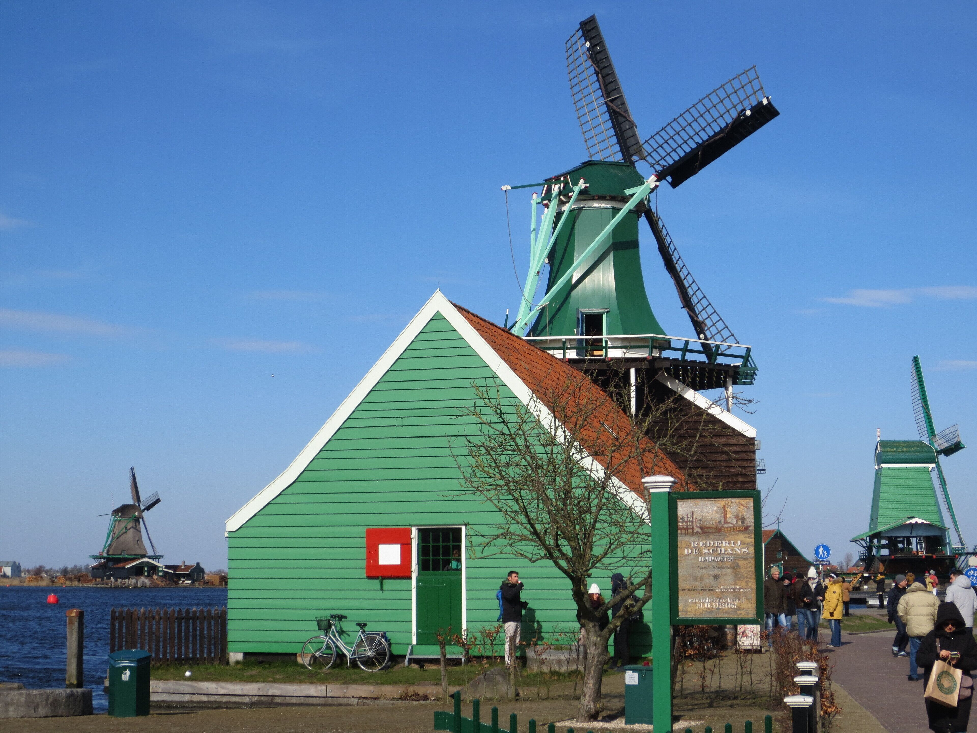 A green building with a windmill, a bicycle, and a signboard.