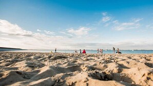 Une plage de sable où l’on voit des gens se promener et s’asseoir.