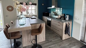Une cuisine moderne avec un îlot central, des tabourets de bar et un vase rempli de fleurs.