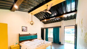 Une chambre à coucher avec un lit, des tables de chevet, un ventilateur de plafond et une vue sur l’extérieur.