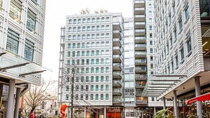 Un edificio moderno en la ciudad con varios pisos, amplias ventanas y un patio central.
