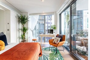 A modern hotel room with a large bed, a desk, a chair, and a balcony with a view of the city. - Idyllic Covent Garden Flat (London)