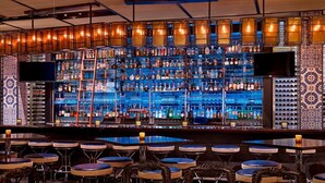 Un'area bar con numerosi scaffali di bottiglie di liquore, una televisione e sgabelli da bar.