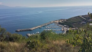 A coastal marina with boats docked, surrounded by greenery and hills. - Air-conditioned apartment with sea view, in a residence in the heart of a 3-hectare park (Cargèse)