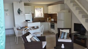 A compact living space with a kitchenette, dining area, and seating area. - Air-conditioned apartment with sea view, in a residence in the heart of a 3-hectare park (Cargèse)