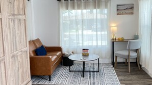 A room with a brown leather sofa, a round table, a wooden cabinet, and a patterned rug. - Shadow Hills Cozy Retreat (Los Angeles)