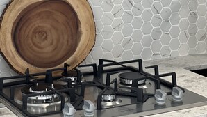 A kitchen with a hexagonal tile backsplash, a round wooden cutting board, and a gas stove. - Shadow Hills Cozy Retreat (Los Angeles)
