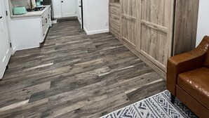 A spacious kitchen with white cabinets, a built-in oven, and a refrigerator. There is a wooden wardrobe with a mirror and a brown leather chair. - Shadow Hills Cozy Retreat (Los Angeles)