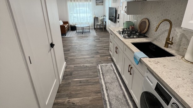 A modern kitchen with white cabinetry, a built-in oven, and a stainless steel sink. - Shadow Hills Cozy Retreat (Los Angeles)