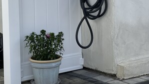 A white door with a wall-mounted charging station and a potted plant beside it. - Shadow Hills Cozy Retreat (Los Angeles)