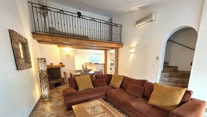 A living room with a brown sectional sofa, a wooden coffee table, and a dining area with a wooden table and chairs. - Charming*** villa with heated pool, close to town center (Porto-Vecchio)
