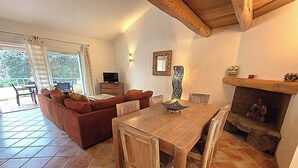 A cozy living area with a wooden dining table, a sofa, and a fireplace. - Charming*** villa with heated pool, close to town center (Porto-Vecchio)