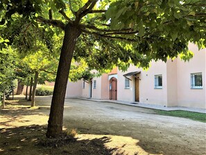 Un pati arbrat amb un edifici que destaca un arc central i nombroses finestres.