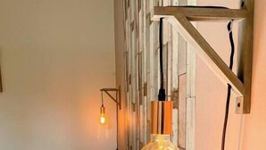A bedroom with a bed, white pillows, a wooden headboard, and a wall-mounted light fixture. - Gites-domainedupin, "gîte de la Closerie (Mosnes)
