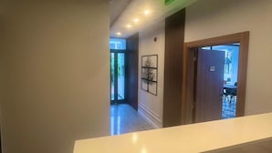 A hotel reception area with a desk, a laptop, and a green exit sign. - Beta Hotel (Istanbul)