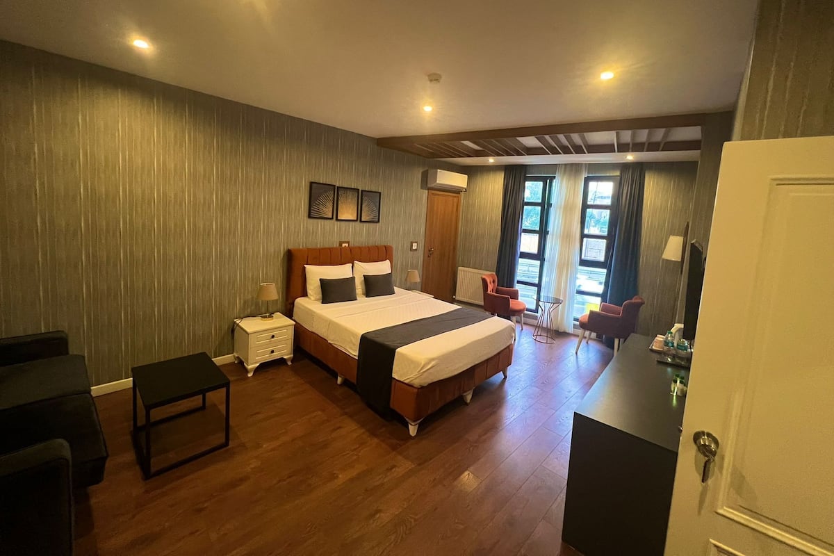 A spacious bedroom with a large bed, a bedside table, a chair, and a small table.