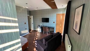 A modern hotel room with a sofa, a desk, a television, and a bed. - Beta Hotel (Istanbul)