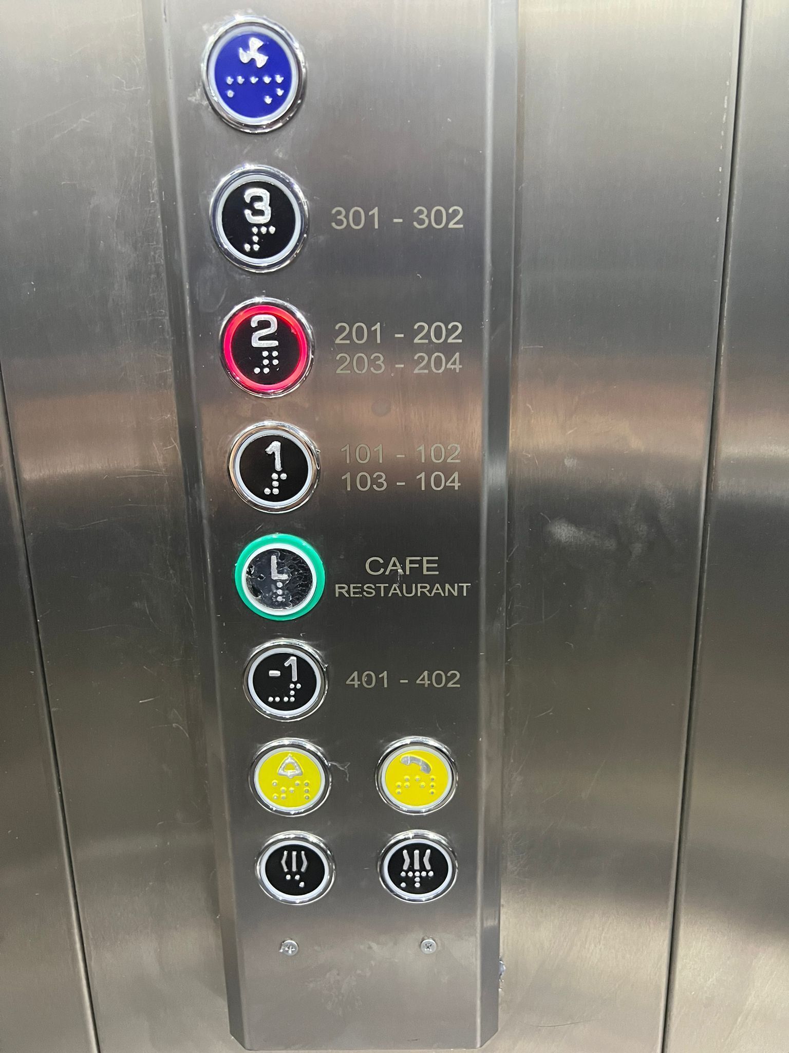 An elevator control panel with floor selection buttons and a cafe restaurant indicator.