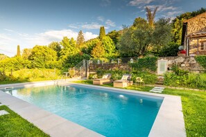 A swimming pool with lounge chairs and a stone building in the background. - Villa Ester in Capannori (Capannori)