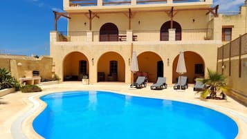 A hotel with a swimming pool, multiple balconies, and outdoor seating areas.