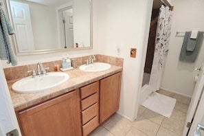 A bathroom with two sinks, a mirror, and a shower curtain.