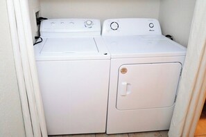 A compact laundry room with two white washing machines and a dryer.