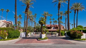 A gated entrance with palm trees, a building with a red roof, and a sign that reads "GOLF CLUB". - Spectacular Music Lovers Condo (Palm Springs)