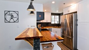 A modern kitchen with a wooden island, stainless steel appliances, and a unique wall art piece. - Spectacular Music Lovers Condo (Palm Springs)